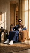 a men sitting on sofa wearing a keffiyeh with thobe