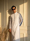 Man wearing a white Saudi thobe with detailing and structured standing collar