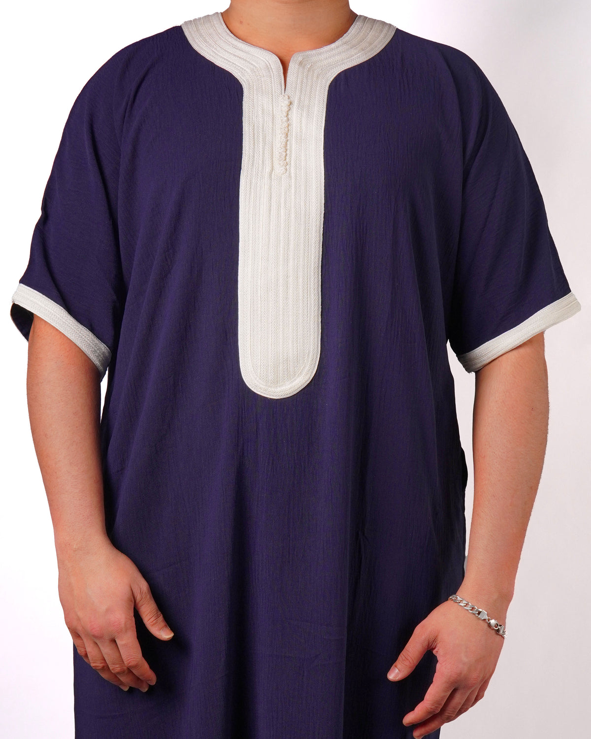 Close-up of the contrast light grey trim on the neckline, placket, and short sleeve cuffs of a men's navy blue thobe.
