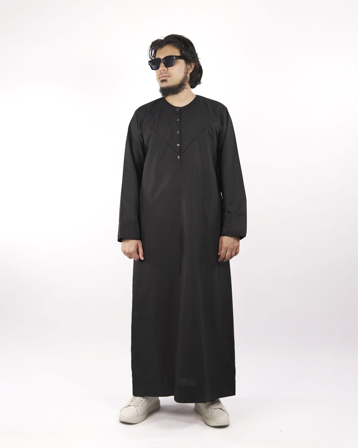 Model wearing a black classic thobe jubba, an example of sophisticated islamic attire for men, full shot.