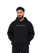 Man wearing black Furqanwear Islamic hoodie, front view with FURQAN wordmark and front pocket