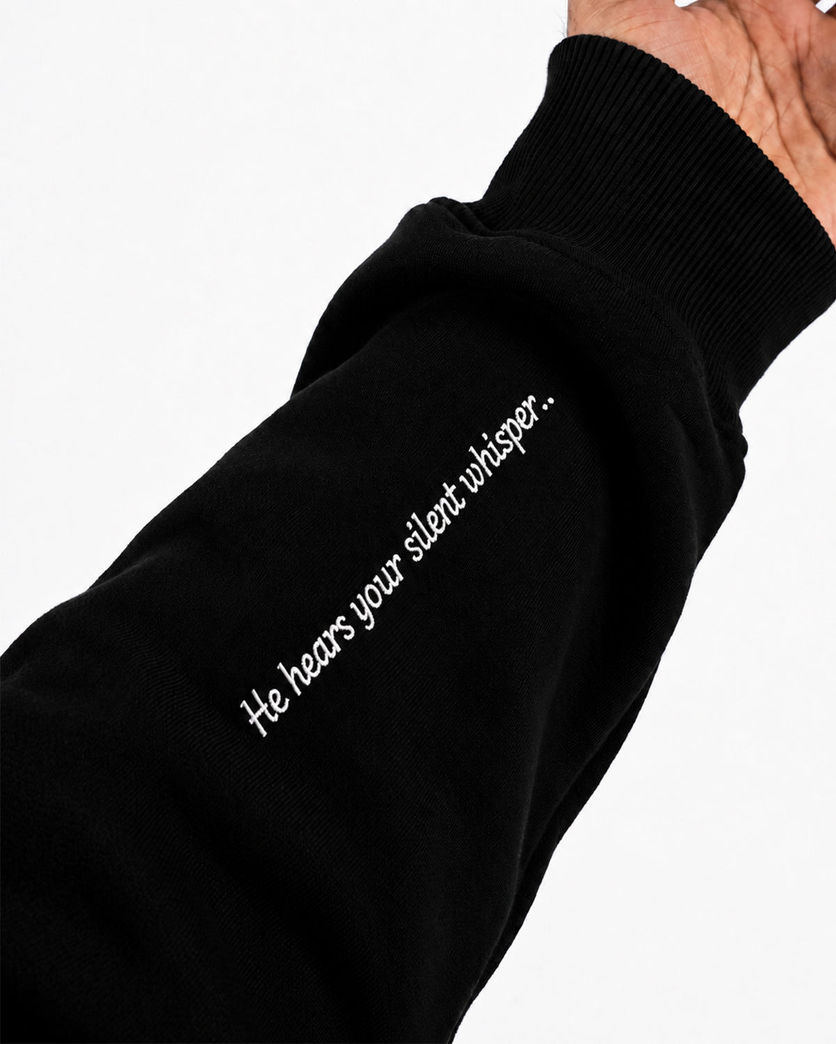 Sleeve of black Furqanwear Islamic hoodie printed with He hears your silent whisper