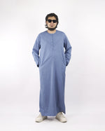 Model wearing a light blue classic thobe with hands in pockets, a comfortable muslim dress for men and stylish islamic attire.