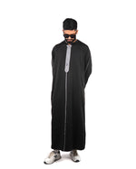  Man standing full length wearing a men's hooded black thobe with silver trim, hands behind back.
