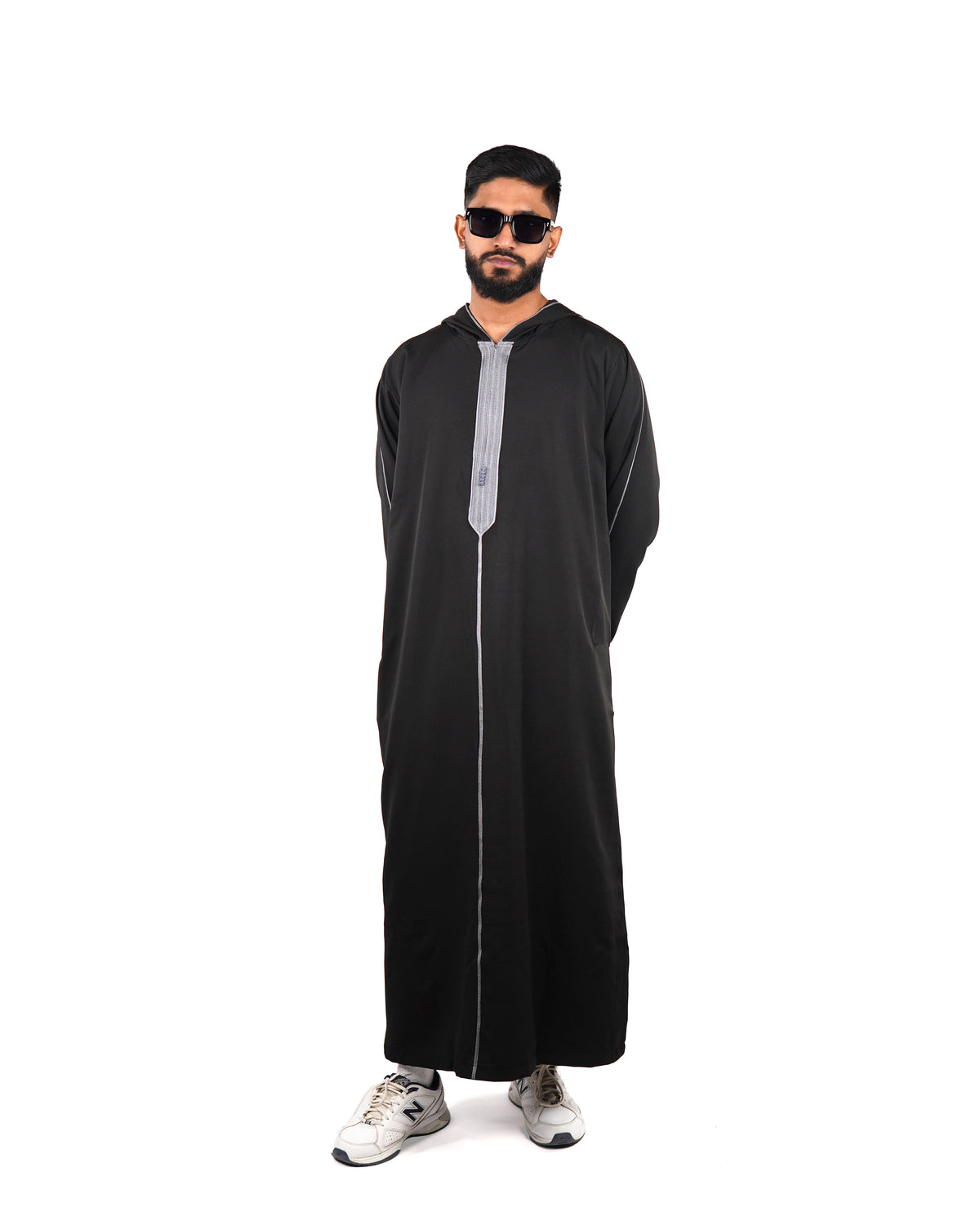 Full length front view of a man wearing a hooded black thobe (or jubba) with silver trim detailing.