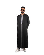 Full length front view of a man wearing a hooded black thobe (or jubba) with silver trim detailing.