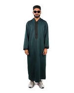 Full length front view of a man wearing a hooded green thobe (or djellaba) with black embroidered trim.