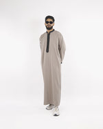 Model presents the Royal Thobe in canvas beige with contrasting black piping, a distinguished choice for islamic clothing for men.