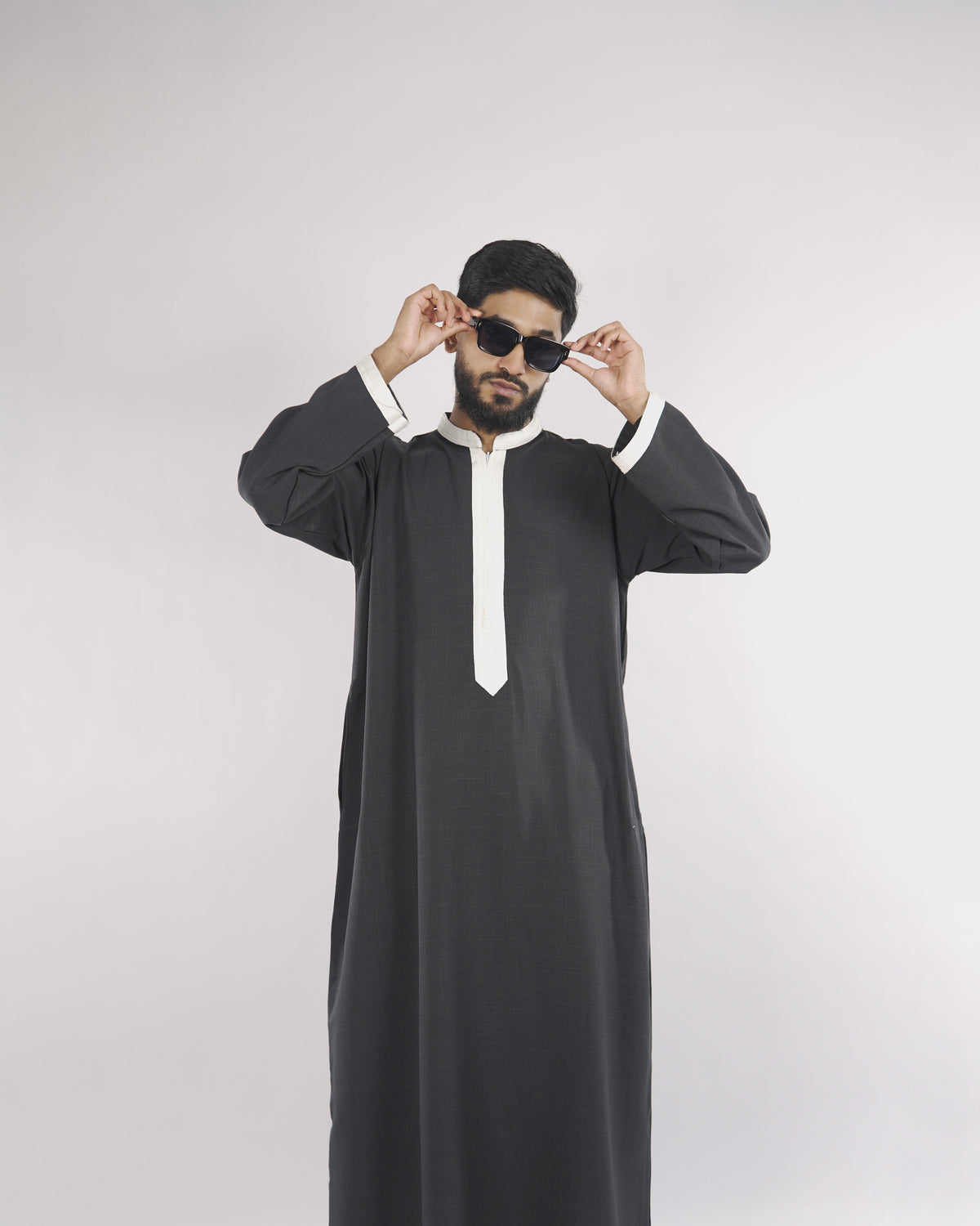 Model wearing the stylish charcoal Royal Thobe with white piping, a distinguished choice for islamic attire for men.