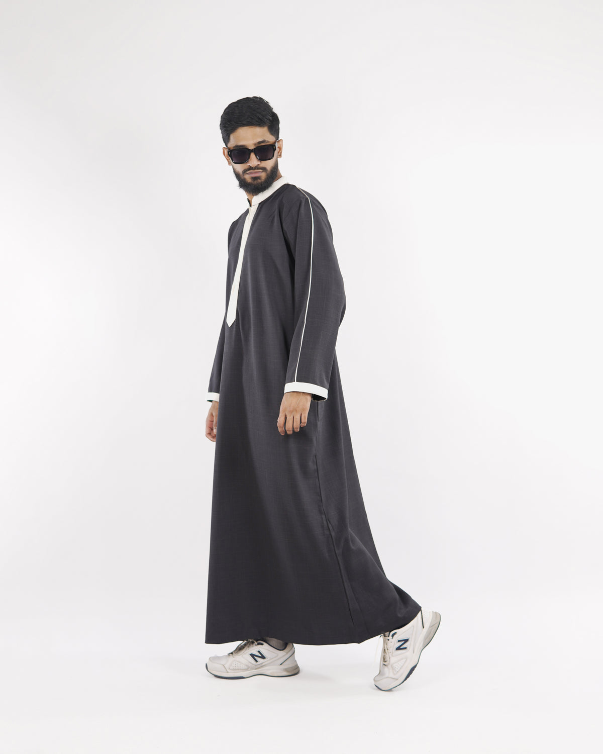 Man models the charcoal Royal Thobe with distinctive white piping, side view, exemplifying refined islamic clothing for men.