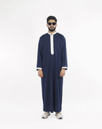 Model showcases the Royal Thobe in deep midnight navy with crisp white piping, a distinguished mens thobe jubba and islamic attire.